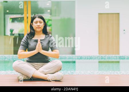 Femme asiatique faisant du yoga assis dans une posture de main de lotus à la maison à l'extérieur. Banque D'Images
