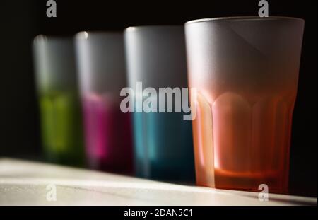 Gros plan sur les verres colorés disposés de suite le compteur de barres est en arrière-plan noir dans des conditions de faible luminosité Banque D'Images