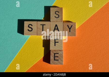 Stay, Safe, mots en lettres de l'alphabet en bois en forme de mots croisés isolés sur fond coloré Banque D'Images