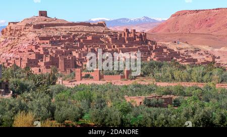 Photo grand angle de jour de Ksar de ait Ben Haddou, avec ses maisons et tours d'abobe, entouré de palmiers et avec les montagnes de l'Atlas à l'arrière Banque D'Images