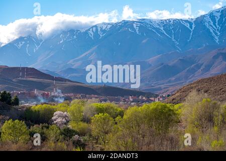 Photo en grand angle de jour d'un magnifique paysage de montagnes enneigées et de buissons et d'un village dans la vallée. Atlas, Maroc. Banque D'Images