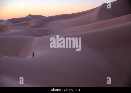 Berbère méconnaissable marchant dans un désert de rêve au crépuscule de l'aube. Dune du désert d'Erg Chigaga, aux portes du Sahara. Maroc. Concept de Banque D'Images