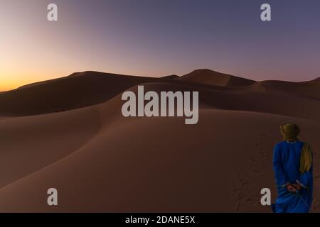 Berbère méconnaissable marchant dans un désert de rêve au crépuscule de l'aube. Dune du désert d'Erg Chigaga, aux portes du Sahara. Maroc. Concept de Banque D'Images