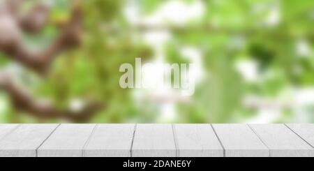 Dossier de table en bois blanc vide avec arrière-plan bokeh vert flou. Pour l'affichage ou le montage de la publicité du produit. Banque D'Images