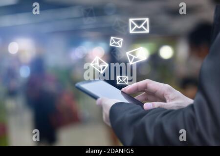 Homme tenant la main à l'aide d'un téléphone portable avec icône d'e-mail à l'écran. Concept de technologie de communication d'entreprise. Banque D'Images