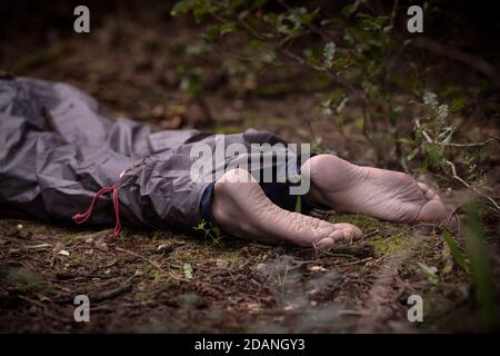 Pieds nus corps mort dans les bois. Meurtre victime couché sur le sol dans la forêt Banque D'Images