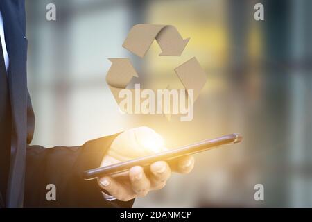 Homme d'affaires main tenant téléphone mobile avec logo de recyclage. Banque D'Images