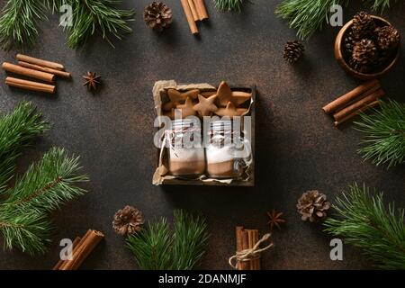 Deux cadeaux de Noël comestibles faits maison dans un pot en verre pour faire des boissons au chocolat et des biscuits sur fond sombre. Banque D'Images