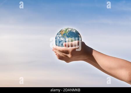 Concept de journée de l'environnement, Globe dans les mains des enfants sur fond bleu ciel. Sauvegarde de la terre. Éléments de cette image fournis par la NASA Banque D'Images