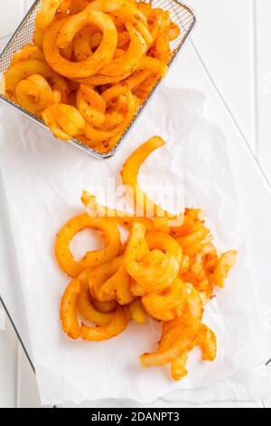 Frites au curly assaisonnées épicées. Prêt à manger sur fond blanc Banque D'Images