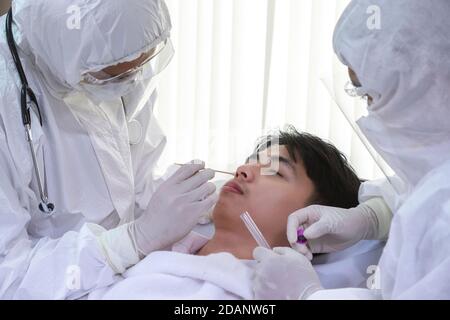 L'infirmière et le médecin portant un costume d'epi et un masque facial effectuent un test PCR du coronavirus COVID-19. Prélèvement d'échantillons par écouvillon nasal NP et OP oral du patient Banque D'Images