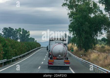 Camion-citerne avec plaque de marchandises dangereuses et étiquette de liquide corrosif sur la route. Banque D'Images