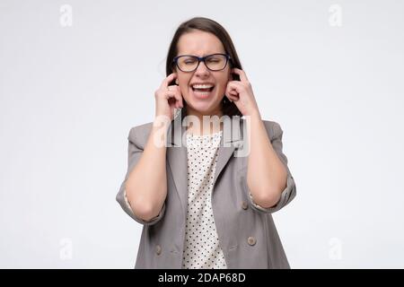 Une femme agacée se branche dans les oreilles sans écouter le son bruit Banque D'Images