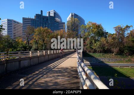 Les gens font du jogging et un vélo sur la passerelle piétonne au-dessus de George Washington parkway, en regardant vers le centre-ville Rosslyn Skyline. À Rosslyn, Arlingt Banque D'Images