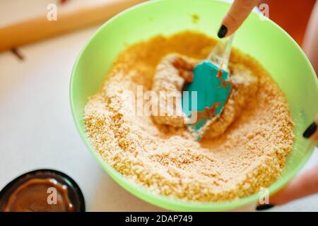 Lait concentré bouilli avec biscuits moulés. La base du gâteau. Spatule à pâtisserie pour mélanger les ingrédients. Fond de cuisson. Cuisson d'un cheesecake classique. Banque D'Images