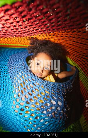 Portrait d'une petite fille africaine heureuse regardant l'appareil-photo pendant jouer dans une aire de jeux intérieure Banque D'Images