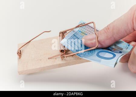 Pouce pris dans un mousetrap en atteignant pour une note de 20 euros sur un fond blanc. Banque D'Images