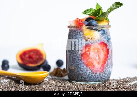 Petit-déjeuner de chia vegan avec des graines de fraise et de chia et une figue, des noix et des myrtilles pour la décoration sur fond blanc Banque D'Images