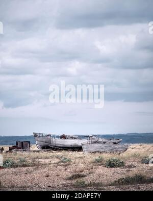 Deux bateaux en bois abandonnés sur le paysage difficile de Dungeness, Kent, Royaume-Uni. Banque D'Images