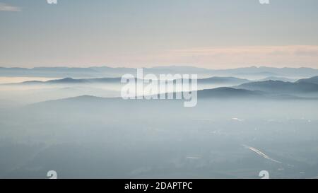 panorama d'un paysage de montagne mystique et romantique avec des couches de sommets de colline se piquant doucement hors des nuages blancs. Brouillard qui coule dans les vallées. Banque D'Images