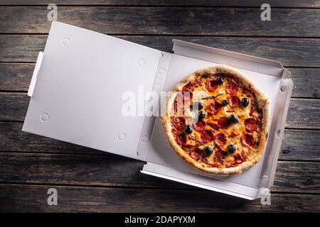 Pizza dans une boîte en carton sur la table, prête pour le client. Banque D'Images