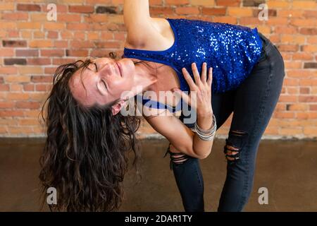 Une vue rapprochée d'une femme qui se plie vers l'avant et étire un bras dans l'air lors d'une routine avancée de yoga Vinyasa Flow pour un corps et un esprit sains Banque D'Images