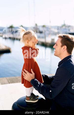 Le père et la fille jouent à Peek-a-boo sur un quai de bateau Banque D'Images