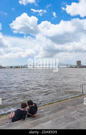 couple regardant le téléphone en étant assis sur les marches près du Mississippi, au bord de la rivière, à la Nouvelle-Orléans, en Louisiane Banque D'Images