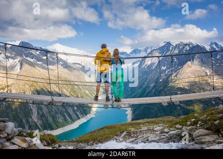 Randonneur, jeune femme et jeune homme sur le pont suspendu à Olpererhuette, réservoir Schlegeis, réservoir Schlegeis, Alpes de Zillertal, Schlegeiskees Banque D'Images