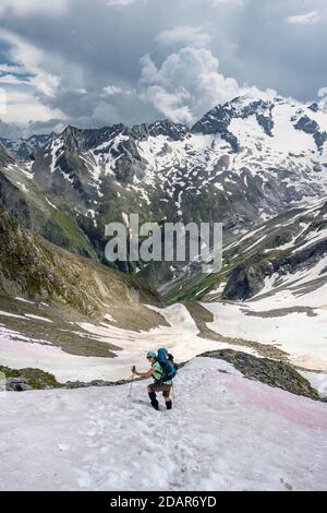 Le randonneur traverse le champ de neige, descente de Moerchnerscharte à Floitengrund, Berliner Hoehenweg, Alpes de Zillertaler, Zillertal, Tyrol, Autriche Banque D'Images