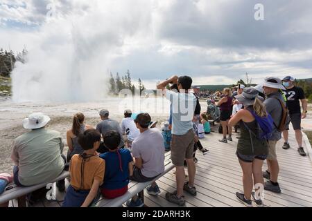 Les visiteurs crossent la promenade alors que Grand Geyser éclate dans le parc national de Yellowstone, Wyoming, le lundi 3 août 2020. Le parc a récemment signalé severa Banque D'Images