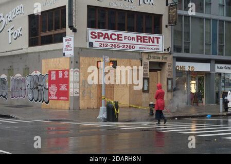 Manhattan, New York. 13 novembre 2020. Une femme traverse la 3ème avenue près d'un restaurant fermé avec un panneau de location. Banque D'Images