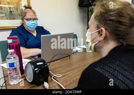 Jen Finch, 40 ans, de Holland, Ohio, prend les informations d'un professionnel de la santé qui se tient pour un patient au centre de test local de la NHA COVID-19 dans l'église chrétienne de la Grande grâce.Neighborhood Health Association (NHA) s'associe à l'église chrétienne de la Grande grâce (GGCC) dans le quartier Auburn-Delaware de Toledo, Ohio, GCC Donner aux résidents de la région l'accès aux tests de laboratoire COVID-19 et à la garde-manger de l'église. NHA a fourni plus de 100 tests COVID-19 à la communauté, et le GGCC a permis aux résidents de partir avec des paniers pleins de provisions. Banque D'Images