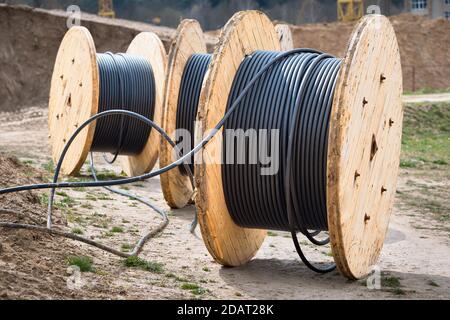 Concept de fourniture d'électricité pour les projets de construction. Plusieurs bobines en bois avec câble d'alimentation posé dans la tranchée. Banque D'Images