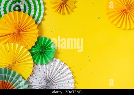 Rosettes de papier multicolore de différents formats sur fond jaune. Décoration et décor pour fêtes, anniversaire ou vacances. Banque D'Images