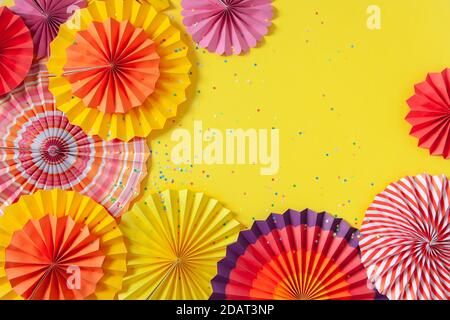 Rosettes de papier multicolore de différents formats sur fond jaune. Décoration et décor pour fêtes, anniversaire ou vacances. Banque D'Images