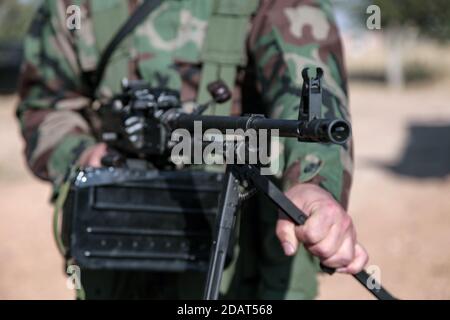 North Homs, Syrie - 2017: Soldat Fighter debout tout en tenant et en pointant le pistolet automatique russe BKC pendant la guerre civile syrienne | gros plan Banque D'Images