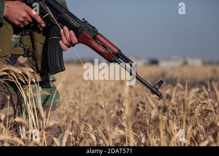 North Homs, Syrie 2017: Soldat syrien tenant une mitrailleuse russe AKS pendant la guerre civile syrienne debout dans un champ de blé agricole Banque D'Images