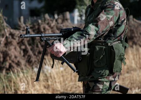 North Homs, Syrie - 2017: Soldat Fighter debout tout en tenant et en pointant le pistolet automatique russe BKC pendant la guerre civile syrienne Banque D'Images