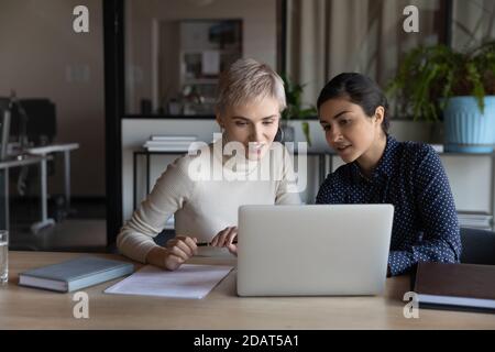 Souriant divers collègues femmes d'affaires travaillant ensemble sur un ordinateur portable Banque D'Images