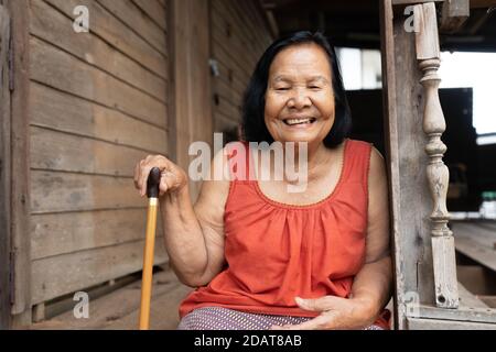 Ralenti de la femme thaïlandaise âgée dans le col rond sans manches rire dans une ancienne maison en bois Banque D'Images