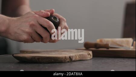 L'homme au ralenti coupe l'avocat mûr pour ouvrir sur la cuisine, photo large Banque D'Images