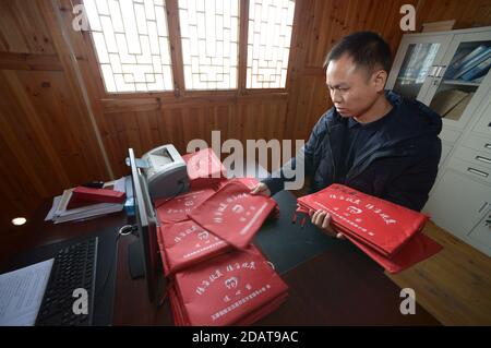 (201115) -- YUPING, 15 novembre 2020 (Xinhua) -- UN fonctionnaire du village trie les dossiers familiaux pauvres au village de Tiejiaxi, dans le comté autonome de Yuping Dong, dans le sud-ouest de la Chine, province de Guizhou, 14 novembre 2020. Le village de Tiejiaxi était l'un des 14 villages en proie à la pauvreté dans le comté. Depuis 2014, le gouvernement local a fait de grands efforts pour aider les villageois à se débarrasser de la pauvreté. D'une part, le gouvernement local a amélioré l'infrastructure et a essayé de conduire les villageois à s'engager dans l'industrie éco-agricole, et d'autre part, il a prêté son soutien aux ateliers locaux de lutte contre la pauvreté afin de les améliorer Banque D'Images