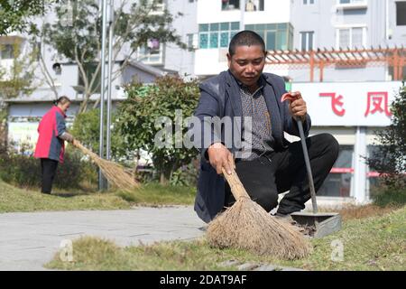 (201115) -- YUPING, le 15 novembre 2020 (Xinhua) -- Yao Maozhong (R), un villageois déplacé, nettoie les feuilles mortes dans la communauté de réinstallation où certains des villageois déplacés du village de Tiejiaxi vivent dans le comté autonome de Yuping Dong, dans la province de Guizhou, dans le sud-ouest de la Chine, le 14 novembre 2020. Le village de Tiejiaxi était l'un des 14 villages en proie à la pauvreté dans le comté. Depuis 2014, le gouvernement local a fait de grands efforts pour aider les villageois à se débarrasser de la pauvreté. D'une part, le gouvernement local a amélioré l'infrastructure et a essayé de conduire les villageois à s'engager dans l'industrie éco-agricole, Banque D'Images