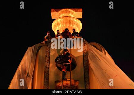 Les manifestants pro-démocratie grimpent sur le monument de la démocratie en utilisant une échelle pour accrocher un énorme feuillet blanc rempli de messages de protestation pendant la manifestation.les manifestants pro-démocratie se sont tournés vers un rassemblement sur le thème du carnaval nommé « Mob Fest » au monument de la démocratie demandant la démission du Premier ministre Prayut Chan-O-Cha, une nouvelle constitution et des réformes de la monarchie. Banque D'Images