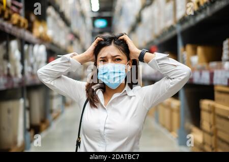 femme stressée avec masque médical dans le magasin d'entrepôt pendant la pandémie du coronavirus (covid-19). Banque D'Images