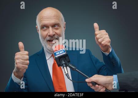 Politicien qui donne un pouce pendant une interview, concept de campagne électorale Banque D'Images