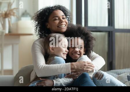 Une femme afro-américaine pleine de joie se câliner avec deux petites filles Banque D'Images