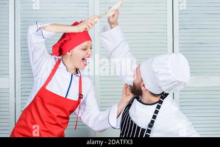 Bataille de deux chefs culinaires. Couple en compétition en arts culinaires Cuisine règles. Qui mieux cuisiner. Bataille culinaire concept. Femme et homme barbu show culinaire concurrents. Cuisine ultime défi. Banque D'Images