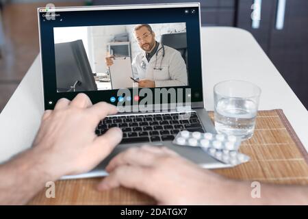 Vue rapprochée de la main d'un patient devant un ordinateur portable lors d'une consultation en ligne avec un médecin. Banque D'Images